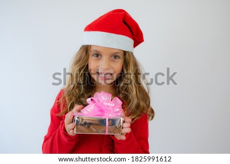 Picture of happy little girl child standing isolated over white background. Looking camera holding gift box surprise.