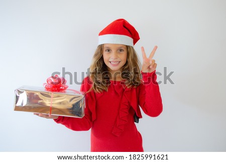 Picture of happy little girl child standing isolated over white background. Looking camera holding gift box surprise.