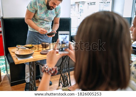 Young cook giving a cooking workshop to a group of people. Selective focus on cook in background