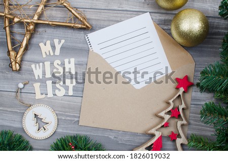 envelope with letter to write Christmas wishes and Christmas decorative objects around. Gold star, wooden tree.