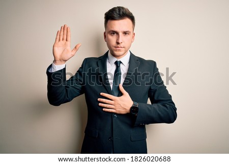 Young handsome business man wearing elegant suit and tie over isolated background Swearing with hand on chest and open palm, making a loyalty promise oath Royalty-Free Stock Photo #1826020688