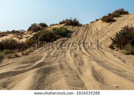 ATV tire tracks up sand dune hill Royalty-Free Stock Photo #1826039288