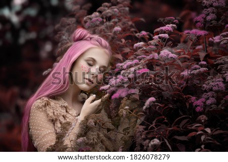 Tender woman with pink hair on the background of flowering bushes