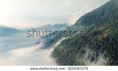 Drone shot over epic mountains above a cloud wall Royalty-Free Stock Photo #1826085278