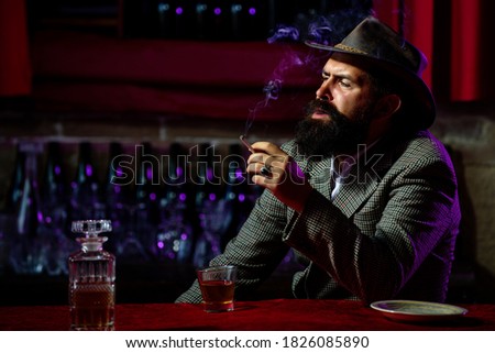 Portrait of a handsome bearded man, with a glass of alcohol in his hands. Rest and relaxation