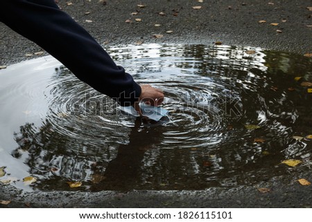 Cleaning of territories from dirty medical masks. A used coronavirus mask floats in a puddle. Dirty puddle. Mask for protection against covid-19. Consequences of covid-19.  Royalty-Free Stock Photo #1826115101