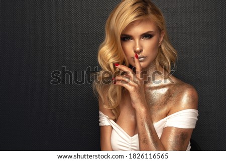 Fashion picture of beautiful young blonde woman wearing glitter silver makeup. Long healthy curly hair.