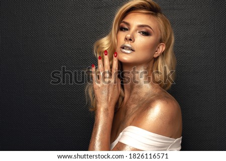 Fashion picture of beautiful young blonde woman wearing glitter silver makeup. Long healthy curly hair.