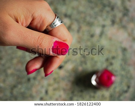 Hand of a young woman painting her red nails
