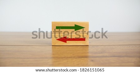 Conceptual image of choice and direction. Wooden blocks with arrows pointing in opposite directions. Beautiful wooden table, white  background, copy space.