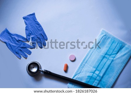 Stethoscope, face mask and hand gloves isolated on blue background