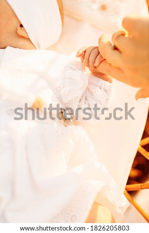 Portrait of cute tiny hand hold mother finger, lovely newborn baby girl laying in the bed, little child look around with big interest, childhood and motherhood concept. High quality photo