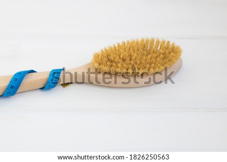 Wooden body brush and measuring tape on a white wooden background. Place for text. Selective focus.