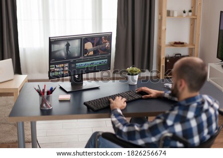 Invalid content creator in wheelchair working on video post production. Disabled videographer doing his business online, using high technology, sitting in his apartment, working remotely in special