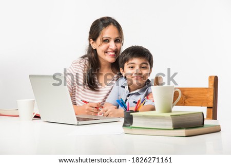 Cute Indian boy with mother doing homework at home using laptop and books - online schooling concept Royalty-Free Stock Photo #1826271161