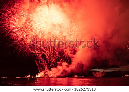Holiday fireworks above water with reflection on the black sky background