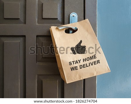 Paper shopping bag on door and text Stay home We deliver