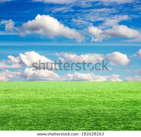Green field under blue clouds sky.