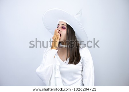 Woman wearing witch costume over isolated white background bored yawning tired covering mouth with hand. Restless and sleepiness.