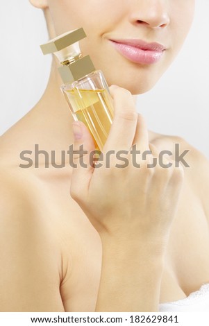 Young woman with perfume on a gray background