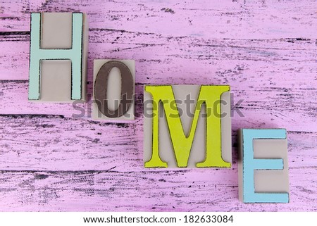 Decorative letters forming word HOME on wooden background