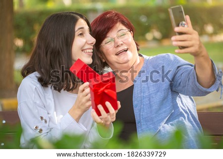 Mature mom and young daughter sharing a gift via video chat.
