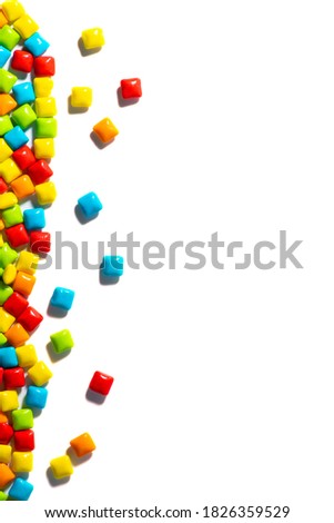Multi-colored candies are located on the left on a white isolated background top view frame. Chewing gum, and dragees are scattered