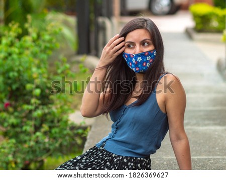 Hispanic Young Woman Sits on the Sidewalk with Blue Flowers Handcraft Face Mask