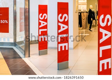 Red bright sale banner on anti-thieft gate sensor at retail shopping mall entrance. Seasonal discount offer in store. High quality photo