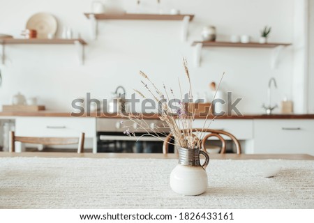 A vase with dry flowers on a table. Scandinavian classic kitchen with wooden and white details, minimalistic interior design. Real photo.Cosy home.