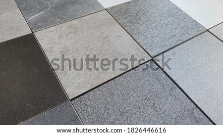 perspective view ,palette of interior stone and concrete tile samples in square shape (focused at center of picture). samples made of granite and quartz stone for flooring ,wall ,counter top works.