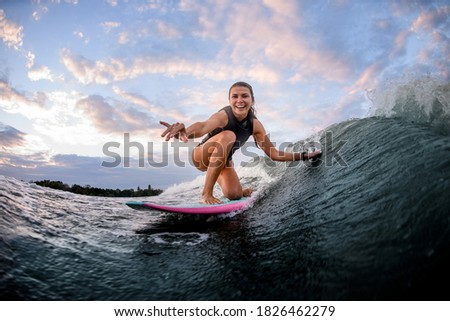 happy young woman rides the wave on surf style wakeboard and touches the wave with one hand Royalty-Free Stock Photo #1826462279