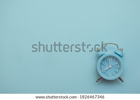 blue clock alarm clock on a light blue background, place for an inscription