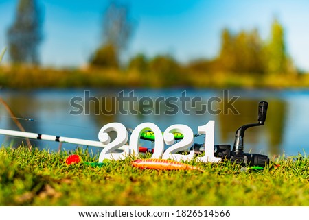 Wooden numbers 2021 on the background of fishing tackle and lures.