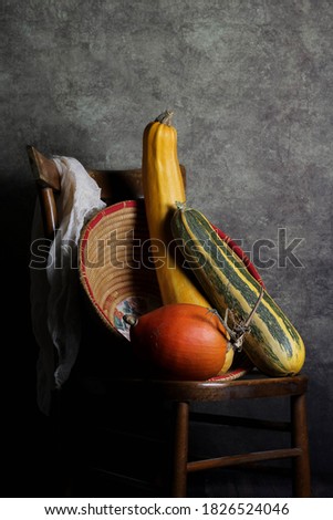 still life food where we find a wooden chair above the pumpkins with a traditional Sardinian basket used in the countryside, a beige muslin on the back