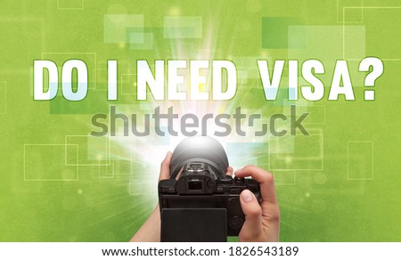 Close-up of a hand holding digital camera with DO I NEED VISA? inscription, traveling concept
