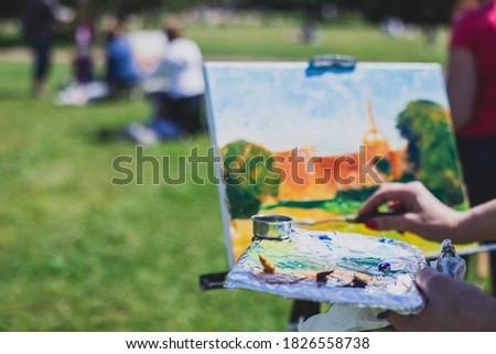 Process of plein air painting, group class of adult talented students in the park with paints easels, and canvases during lesson of watercolour painting outdoors 