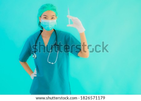 Portrait beautiful young asian doctor woman wear mask with syringe vaccine for protect from covid19 or coronavirus on blue isolated background