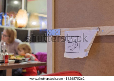 Selected focus at protective face mask covering mouth and nose symbol on white sign on wooden partition in restaurant during  COVID-19 virus and German face mask regulations for Social distancing.