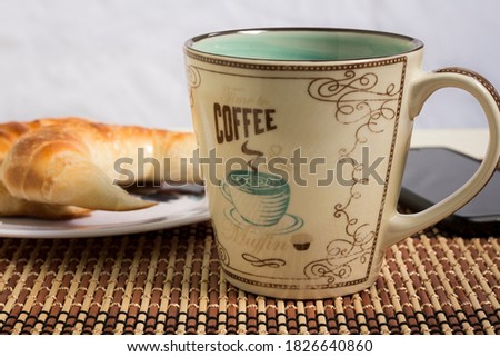 Picture of a cup of coffee, a plate with croissants and a mobile phone