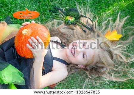 girl in a witch costume for the Halloween holiday. Happy girl lies on the grass