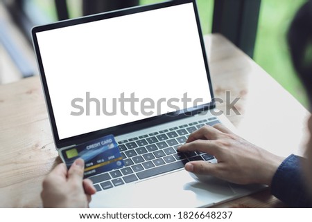 Man using blank laptop and credit card sending massages shopping online.