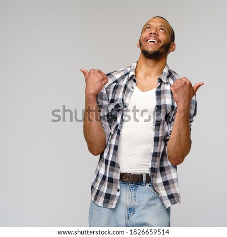 african-american young man wearing casual shirt and showing thumbs up over light grey background
