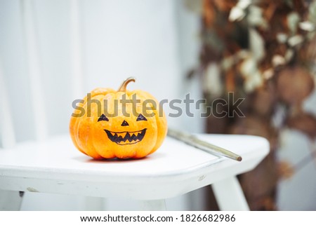 Halloween Pumpkin. Evil Halloween pumpkin on a white chair and next to it is magic wand. Soft focus on the right eye.