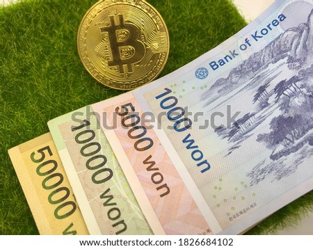 Money; South Korean Won (KRW) banknote and bitcoin on grass background. - Business, Finance and Economy Concept.