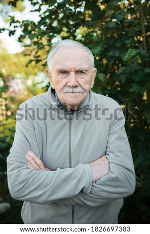 serious gray-haired old man attentively looks at the interlocutor. Portrait of a beautiful old man close-up