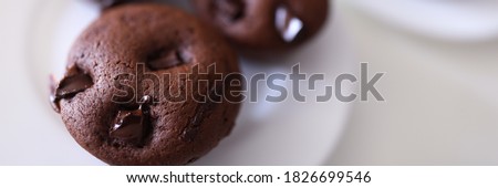 Close-up of delicious chocolate muffins with crispy top served on white plate. Homemade tasty cupcakes with cocoa stuffing. Unhealthy food. Yummy dessert and sweets concept