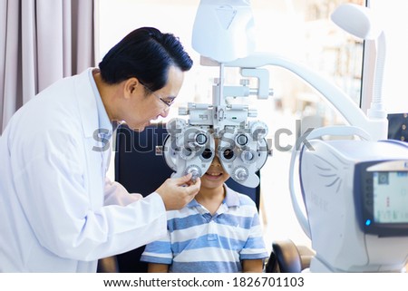 An Asian male doctor examines a child's vision. optometrists man are examining pediatric patients' eyes with the Autorefractor in a clinic. Royalty-Free Stock Photo #1826701103