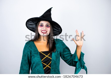 Woman wearing witch costume over isolated white background doing hand symbol