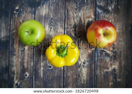 Green apple, red apple and yellow pepper on a blackboard background